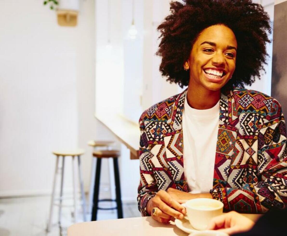 smilende kvinde i farverigt tøj på cafe