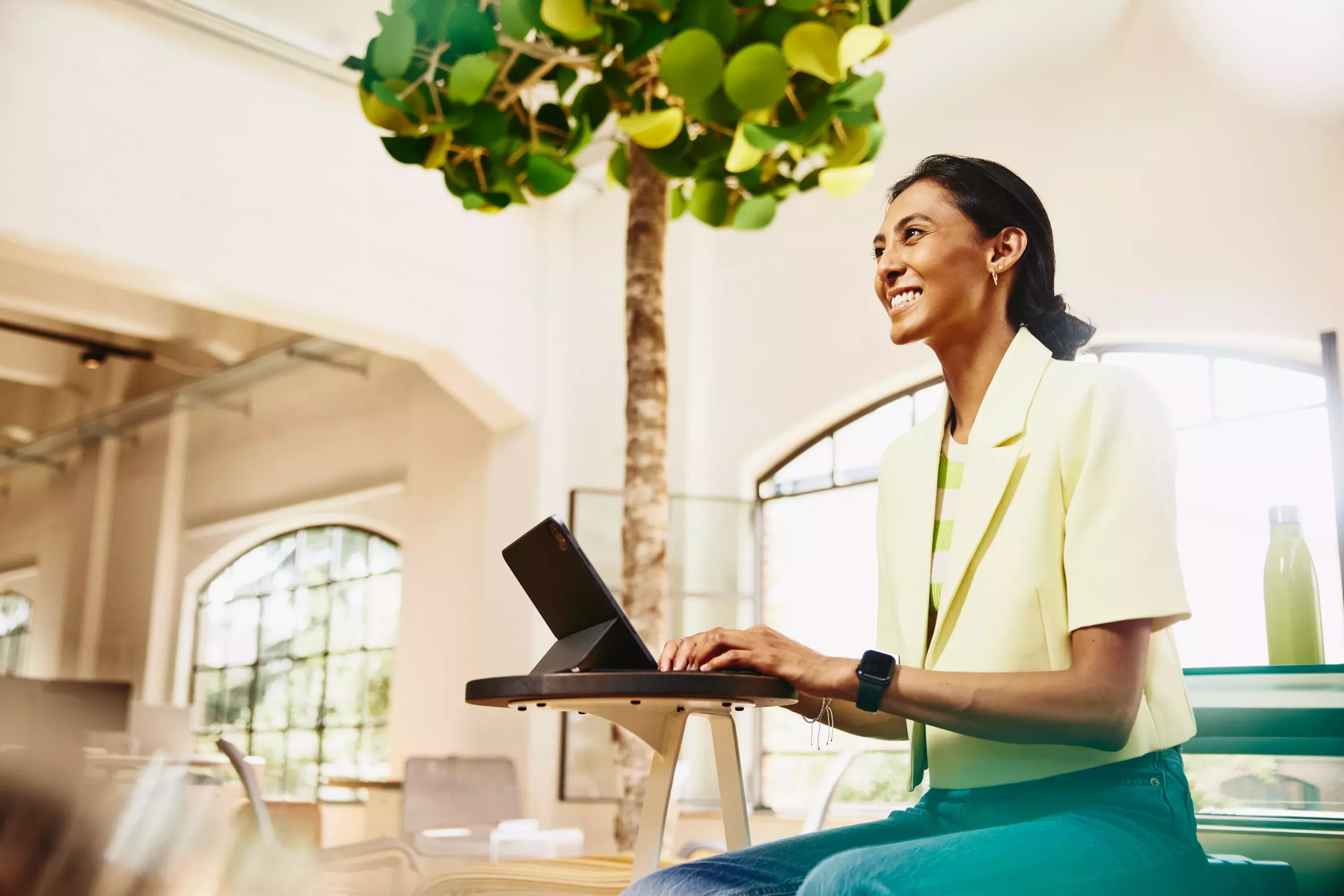 Smiling female sitting at table working on a tablet.
