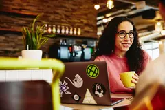 Close up - Smiling female holding a mug while talking to someone.
